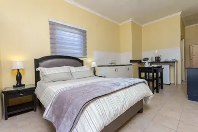a bedroom with a large bed and a kitchen at Kingfisher Hollow in Gordonʼs Bay