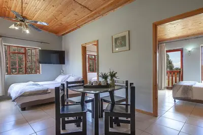 a bedroom with a dining room table and a bed at Kingfisher Hollow in Gordonʼs Bay