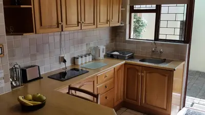 a kitchen with wooden cabinets and a sink and a table at Eikepark Self Catering in Stellenbosch