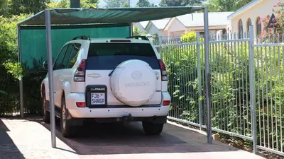 a small white car parked next to a fence at Eikepark Self Catering in Stellenbosch