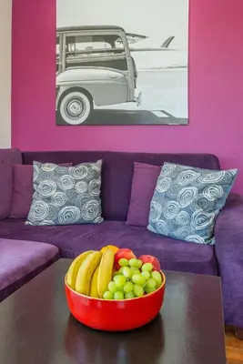 a bowl of fruit on a table in front of a purple couch at da Heim Guest House in Cape Town