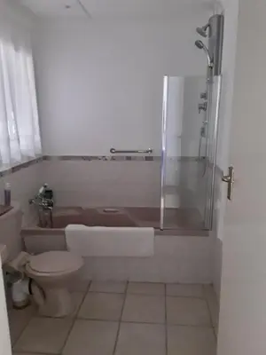 a bathroom with a tub and a toilet and a shower at Fijnbos Manor in Bettyʼs Bay