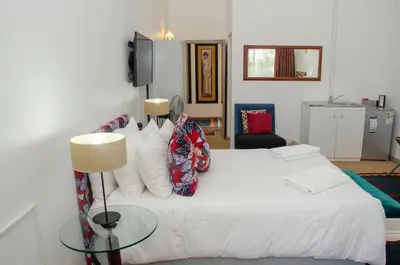 a bedroom with a white bed with a glass table at Fijnbos Manor in Bettyʼs Bay