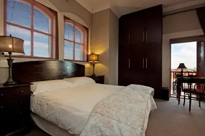 a bedroom with a large bed and a desk and a window at A Smart Stay Apartments in Somerset West