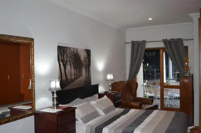 a bedroom with a bed and a mirror and a chair at A Smart Stay Apartments in Somerset West