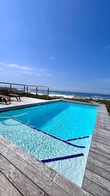 a swimming pool with a view of the ocean at Kallistes Misty Shores Cottage in Bettyʼs Bay