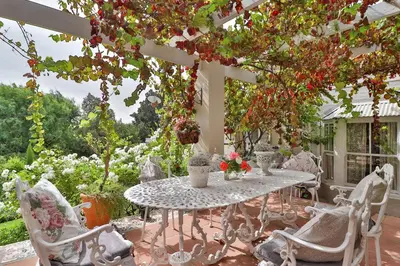 a white table and chairs on a patio with flowers at Three Oaks in Durbanville