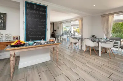 a dining room with a table and chairs and a chalkboard at Oude Schuur Boutique Guesthouse in Hermanus