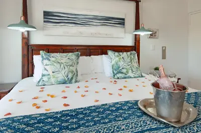 a bed with flowers on it with a bucket on it at Oude Schuur Boutique Guesthouse in Hermanus