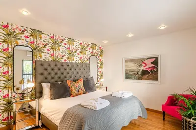 a bedroom with a bed and a wall with flowers at The Ivy Apartments Franschhoek in Franschhoek