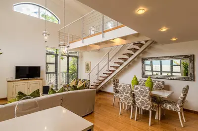 a living room with a staircase and a table and chairs at The Ivy Apartments Franschhoek in Franschhoek