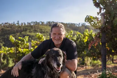 a man posing with a dog in a vineyard at Muratie Wine Estate in Stellenbosch