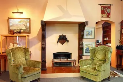 a living room with two chairs and a fireplace at Muratie Wine Estate in Stellenbosch