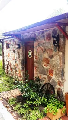 a stone house with a wooden door and a wheel at Matshana Lodge in Hermanus