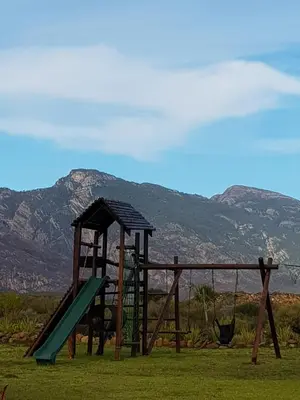 a playground with a slide in the grass with mountains at Windfall Wine Farm in Robertson