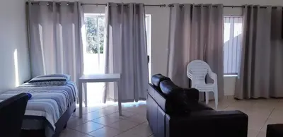 a bedroom with a bed and a chair and a table at Getaway Self-Catering Tyger Valley in Durbanville