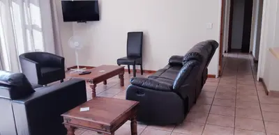 a living room with black leather furniture and a tv at Getaway Self-Catering Tyger Valley in Durbanville