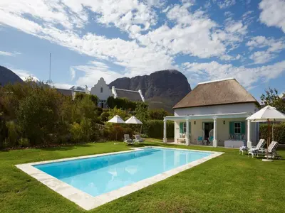 a villa with a swimming pool and a house at La Cotte House in Franschhoek