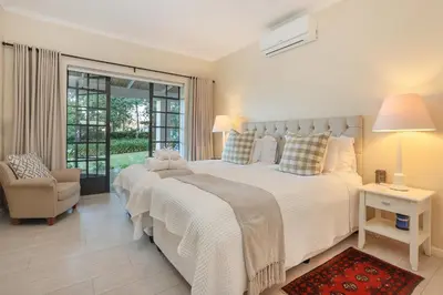 a white bedroom with a large bed and a chair at Elgin Country Lodge in Elgin