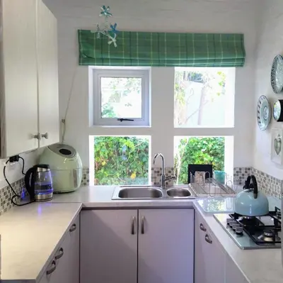 a kitchen with a sink and two windows at Festina Lente in Onrus in Hermanus
