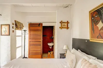 a bedroom with a bed and a bathroom with a sink at Festina Lente in Onrus in Hermanus