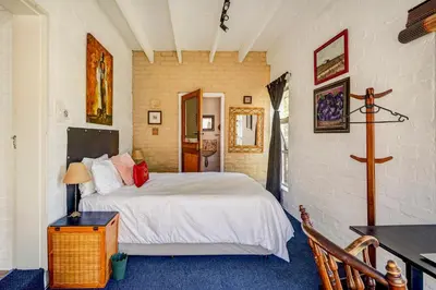 a bedroom with a white bed and a table at Festina Lente in Onrus in Hermanus