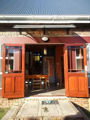 an open door of a house with a table at Festina Lente in Onrus in Hermanus