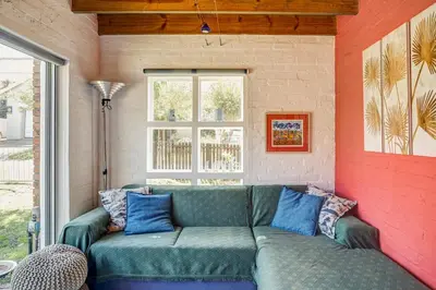a living room with a green couch against a brick wall at Festina Lente in Onrus in Hermanus