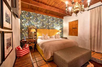 a bedroom with a bed and a table with a chair at Avondrood Guest House by The Oyster Collection in Franschhoek