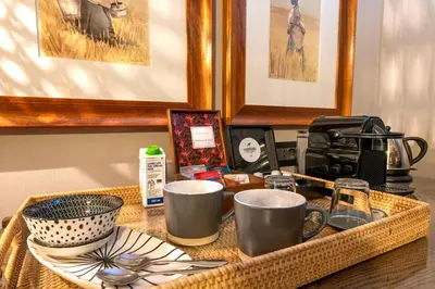 a table with a basket with cups and dishes on it at Avondrood Guest House by The Oyster Collection in Franschhoek
