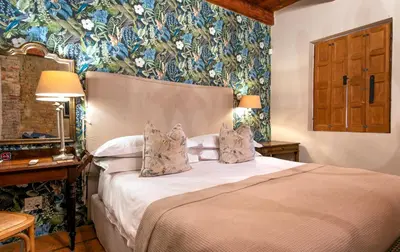 a bedroom with a bed with floral wallpaper at Avondrood Guest House by The Oyster Collection in Franschhoek