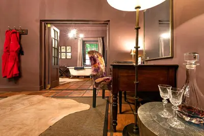 a woman sitting in a chair in a room with a mirror at Avondrood Guest House by The Oyster Collection in Franschhoek