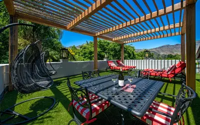a patio with a table and chairs and a swing at Avondrood Guest House by The Oyster Collection in Franschhoek