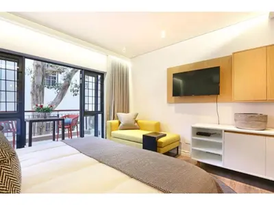 a living room with a bed and a tv and a couch at Eikehoff Apartments in Stellenbosch