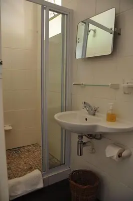 a bathroom with a sink and a shower with a mirror at Kierie Kwaak Self Catering in Stellenbosch