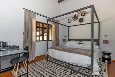a bedroom with a canopy bed and a desk at Africa Lodge in Somerset West