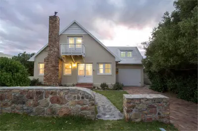 a house with a stone wall in front of it at Stone Chimney Cottage in Hermanus