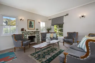 a living room with chairs and a fireplace at Stone Chimney Cottage in Hermanus
