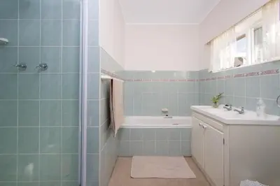 a bathroom with a tub and a sink at Stone Chimney Cottage in Hermanus
