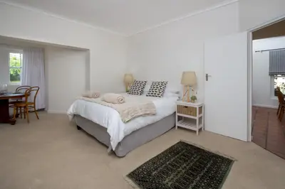 a white bedroom with a bed and a table at Stone Chimney Cottage in Hermanus
