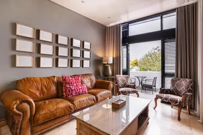 a living room with a brown leather couch and a table at Avemore Eikehoff No 23 - full Backup Power in Stellenbosch