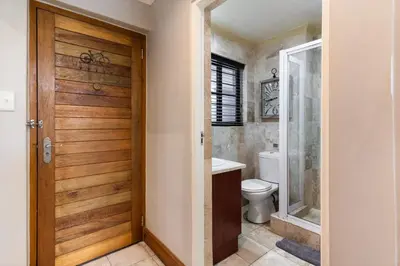 a bathroom with a toilet and a wooden door at Avemore Eikehoff No 23 - full Backup Power in Stellenbosch