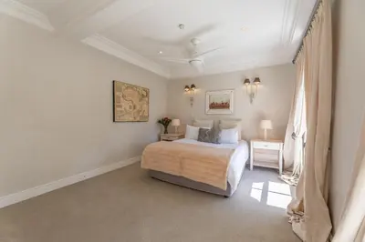 a white bedroom with a bed and a window at Maison du Cap in Cape Town