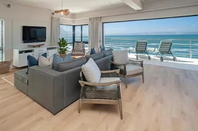 a living room with a couch and chairs and a television at Hamewith Penthouse in Hermanus