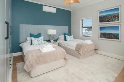 two beds in a room with blue walls at Hamewith Penthouse in Hermanus