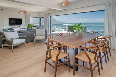 a dining room with a table and chairs and a living room at Hamewith Penthouse in Hermanus