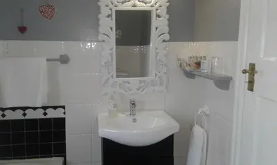 a white bathroom with a sink and a mirror at Eastbury Cottage in Hermanus