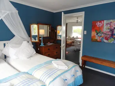 a bedroom with two beds and a blue wall at Eastbury Cottage in Hermanus