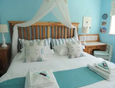 a bedroom with a large white bed with white pillows at Eastbury Cottage in Hermanus