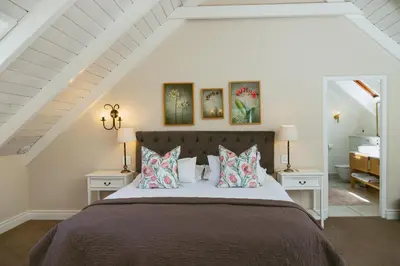 a bedroom with a bed with pillows and two tables at Auberge Clermont in Franschhoek